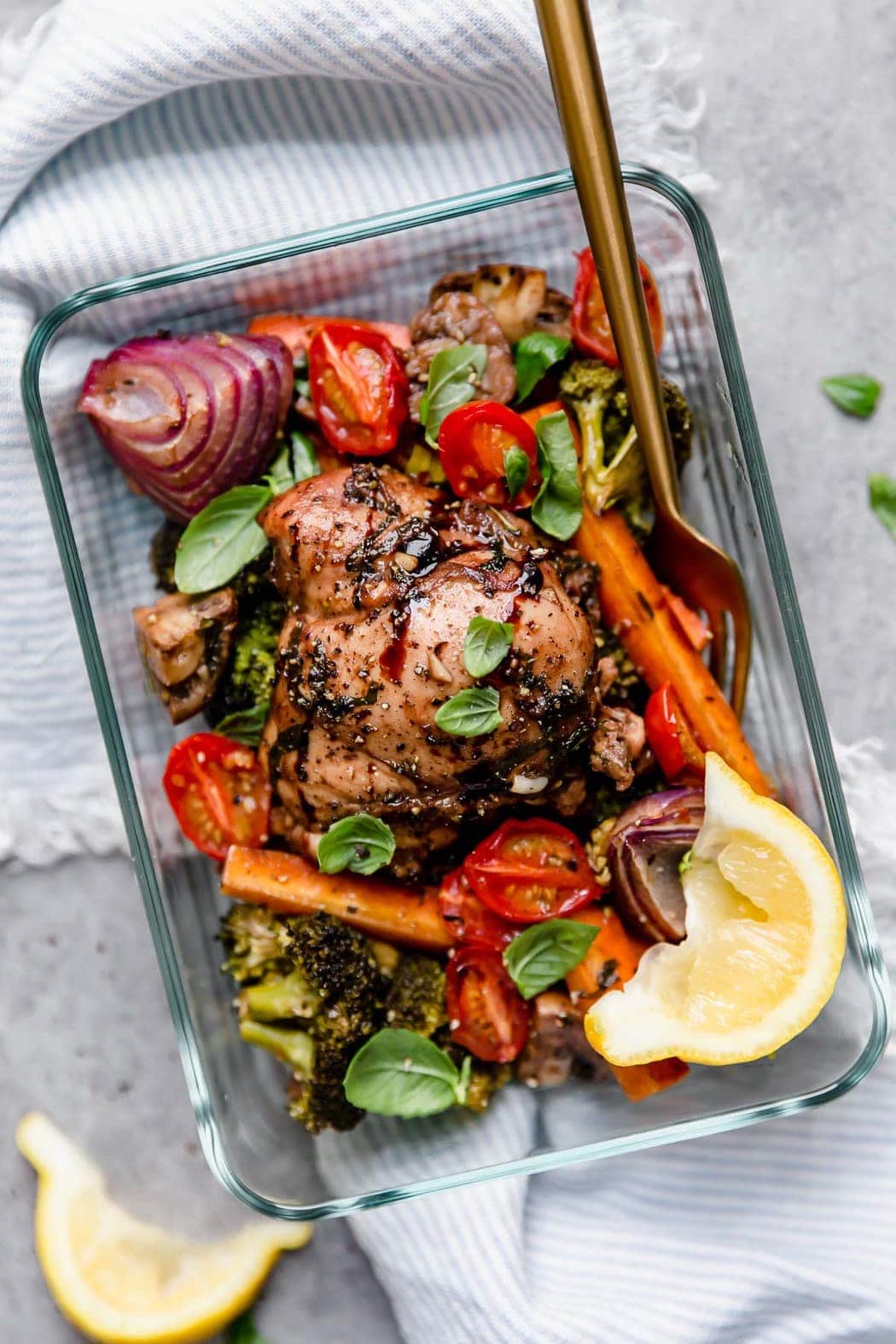 Overhead view of a glass meal prep container filled with balsamic chicken and vegetables.