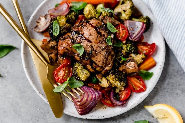 Close up view sheet pan balsamic chicken veggie bake served on stone plate
