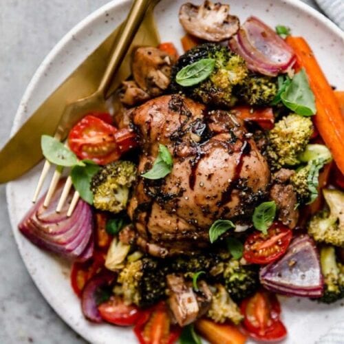 Overhead view serving of sheet pan balsamic chicken and veggies on plate with gold cutlery