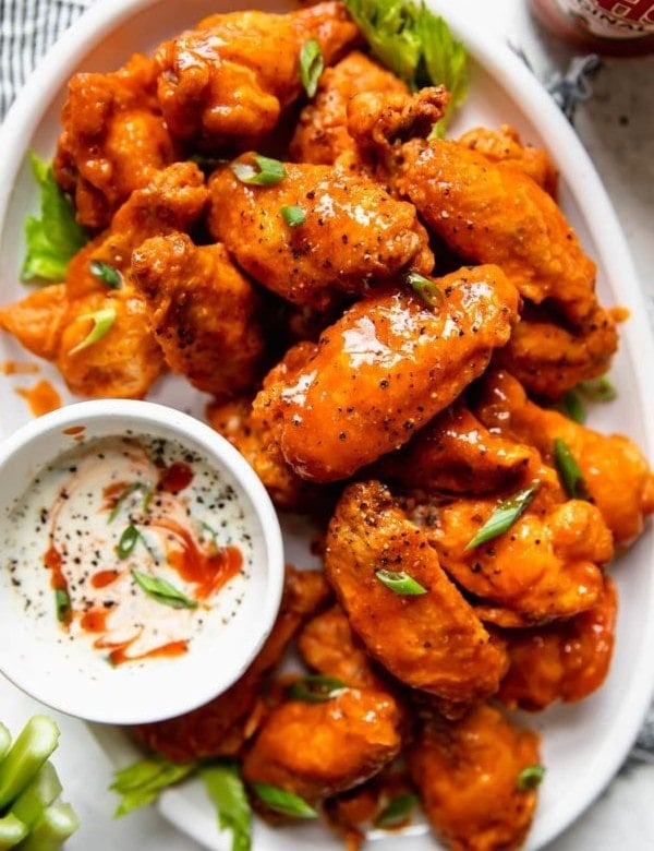 Overhead view of a platter of crispy baked buffalo wings on a white platter