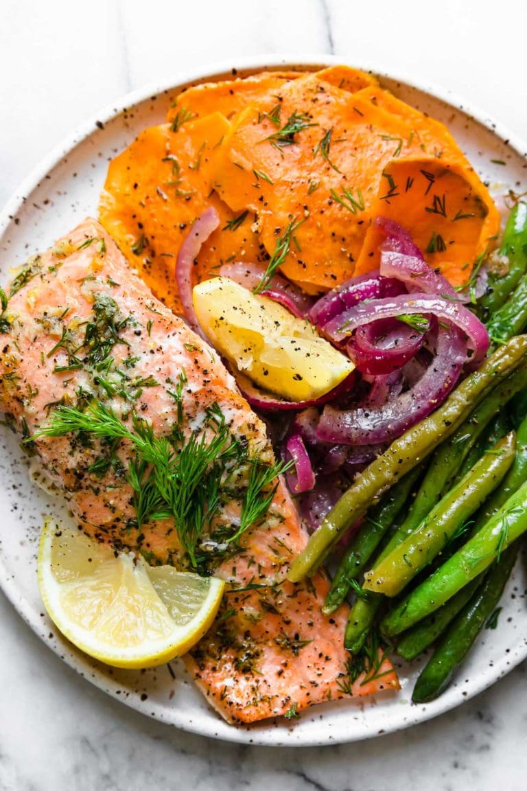 Sheet Pan Baked Salmon with Vegetables and garnished with lemon and fresh dill. 