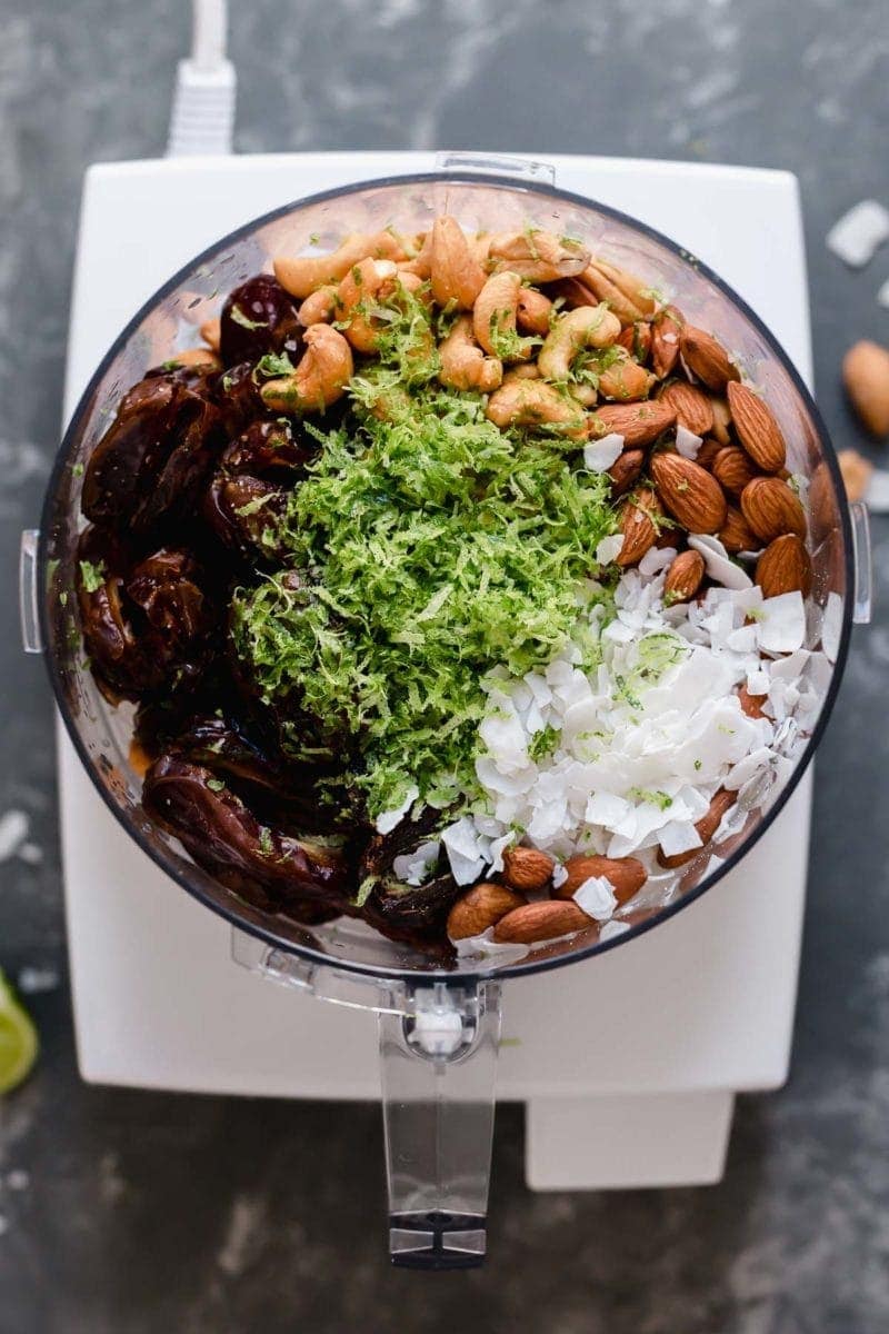 Food processor bowl filled with ingredients for key lime energy bars