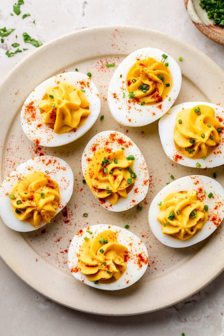 Overhead view of a platter of Greek yogurt deviled eggs topped with fresh chives and sprinkled with paprika.
