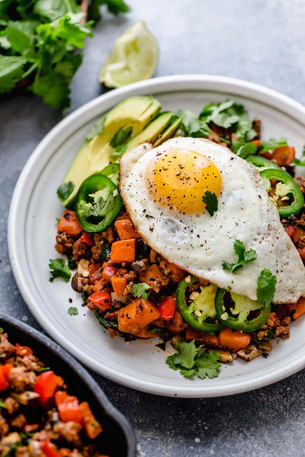 Tex-Mex Sweet Potato Hash served on a white plate with a fried-egg on top.