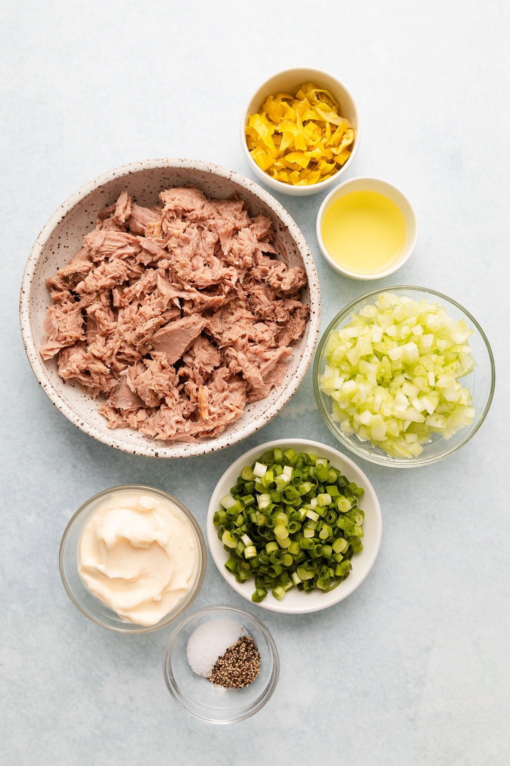 Overhead view of a variety of ingredients for Tuna Salad in different sized bowls.