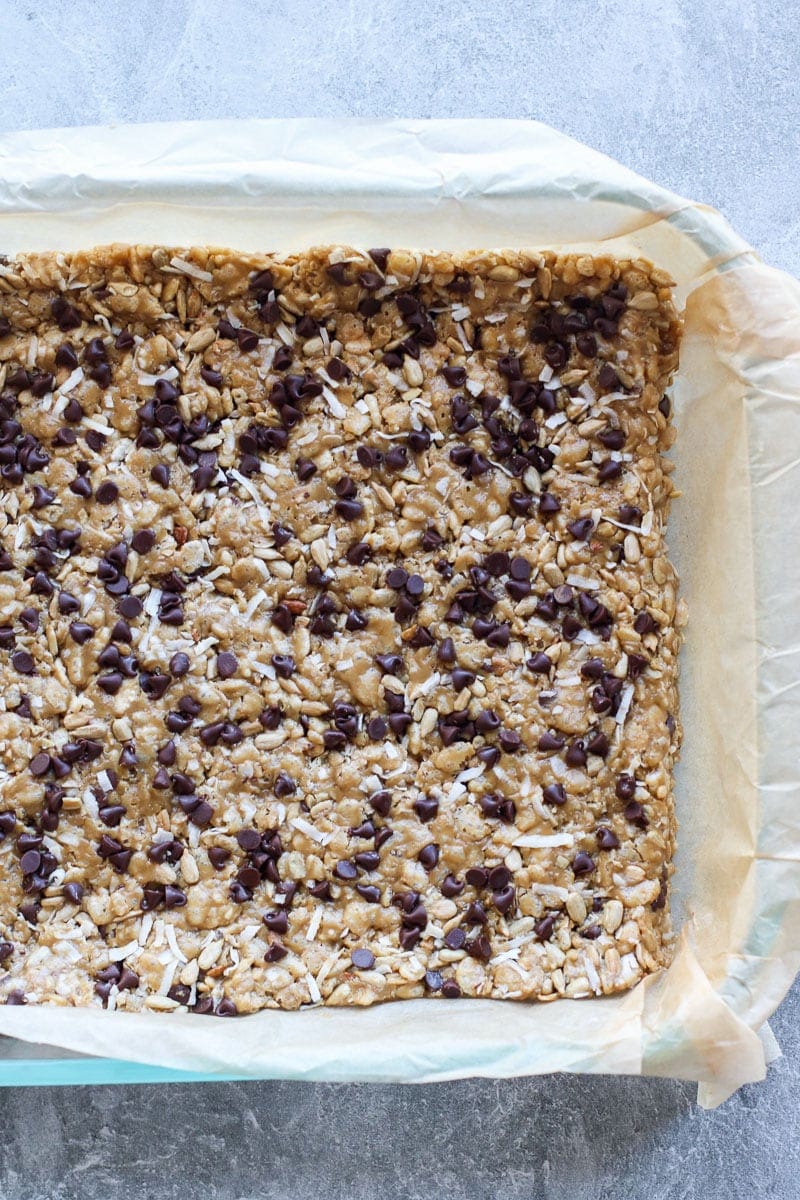 Soft and chewy chocolate chip granola bars pressed into a baking dish ready to cut into bars