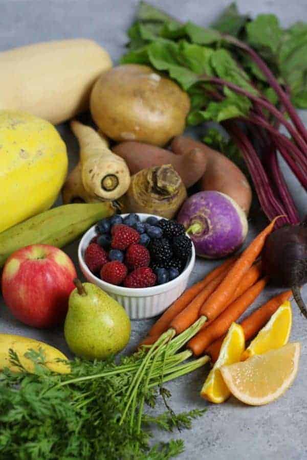 A variety of colorful fresh fruits and vegetables on a gray countertop. 