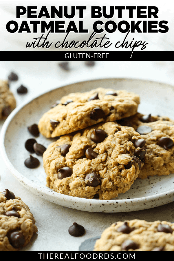Three peanut butter oatmeal cookies on a cream speckled pate with chocolate chips scattered around it