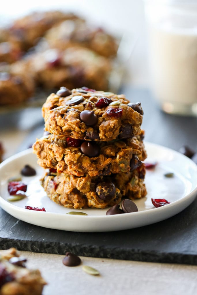 Three healthy oatmeal breakfast cookies stacked up on a white plate.