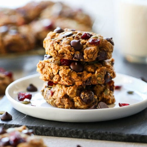 Three oatmeal pumpkin breakfast cookies stacked up on a white plate.