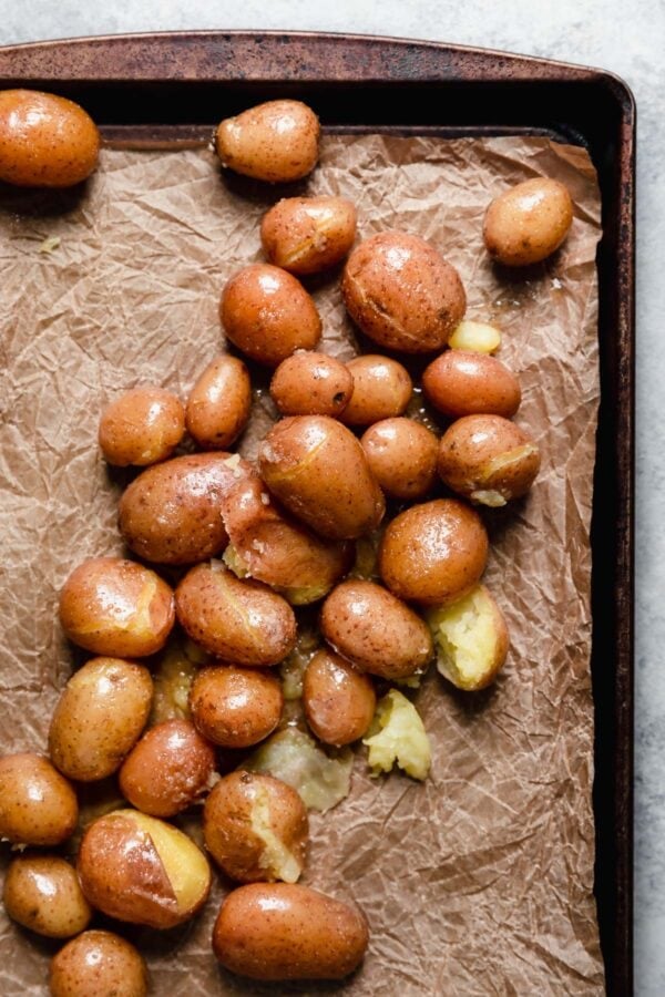 A sheet pan filled with roasted potatoes with garlic herb oil on top