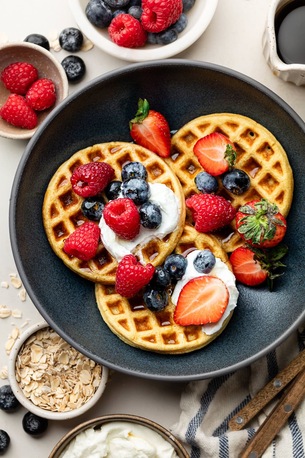 Overhead view of a plate of Protein Waffles topped with yogurt and fresh berries. 