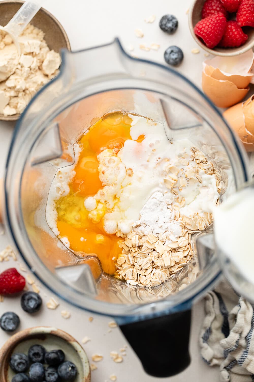 Overhead view of a blender filled with Protein Waffles ingredients ready for blending. 