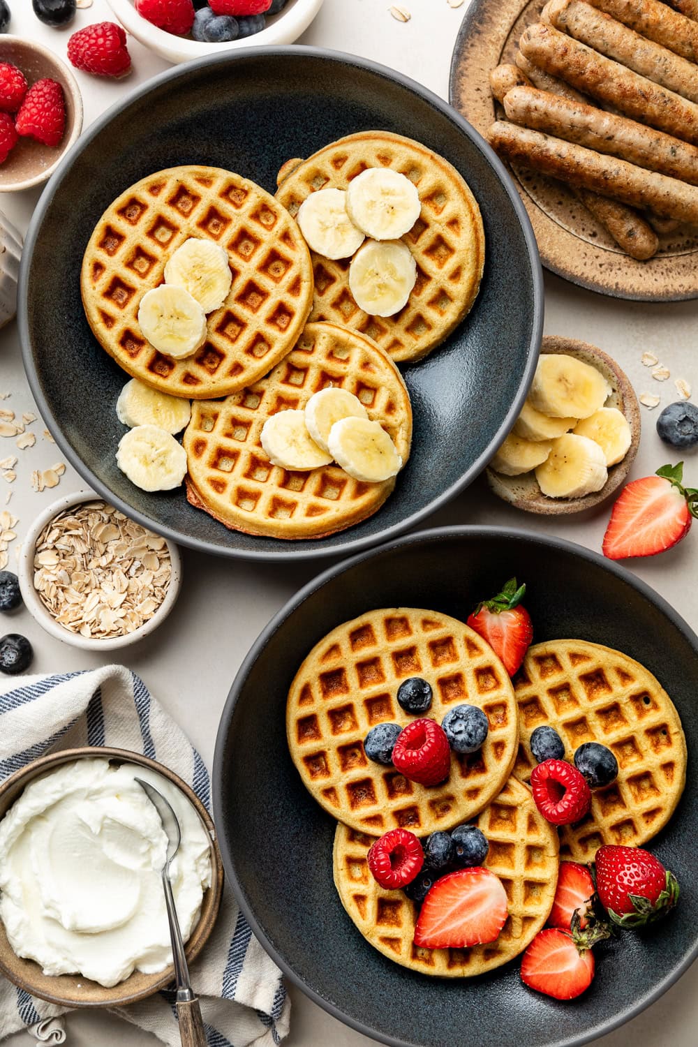 Overhead view of two plates filled with Protein Waffles topped with fresh fruit. 