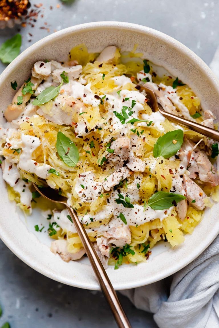 Overhead view of a plate filled with chicken alfredo on top of baked spaghetti squash and drizzled with creamy alfredo sauce. 