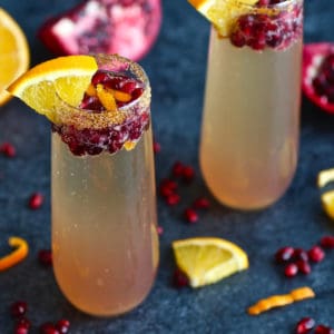 2 Pomegranate Kombucha Mimosas with fresh oranges and pomegranate pieces