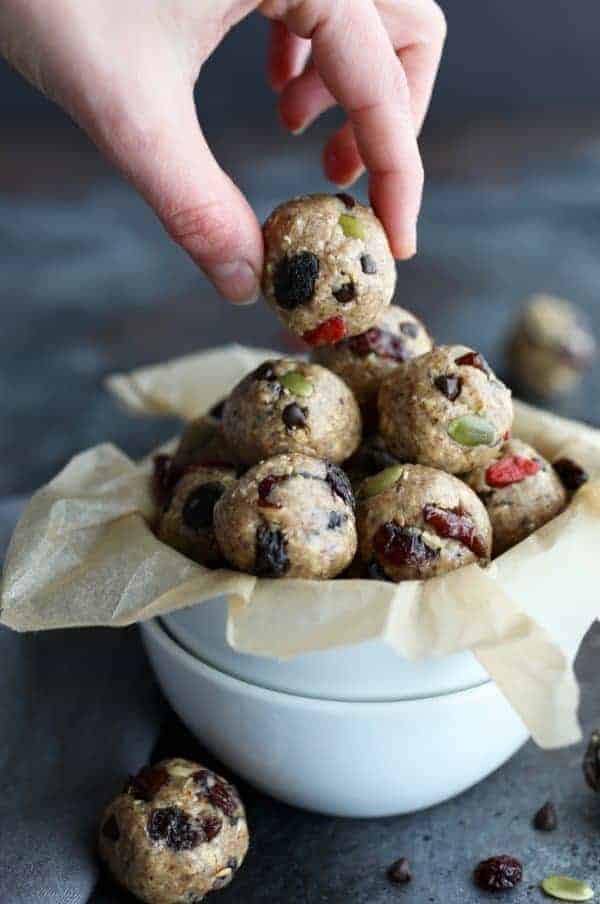 Hand grabbing an energy bite from a bowl.