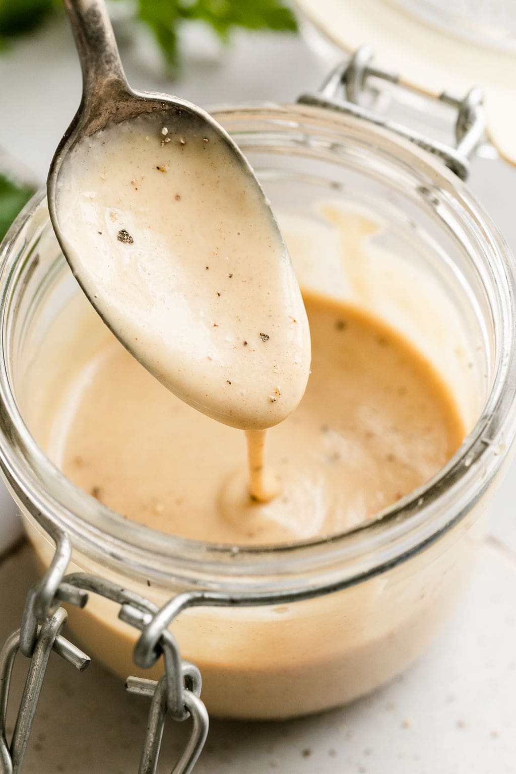 Honey mustard sauce drizzling off a spoon into glass jar