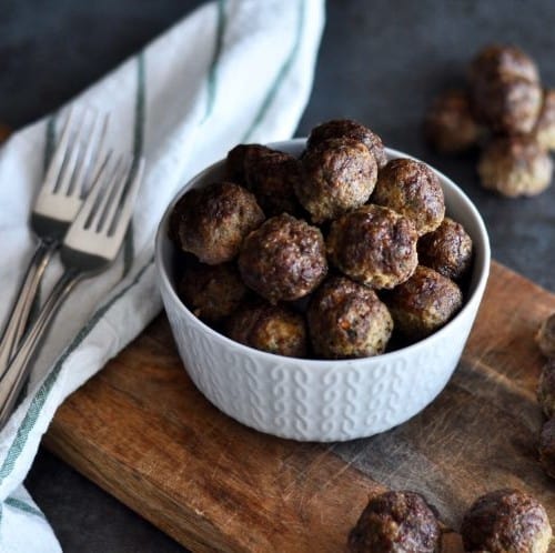 A bowl of Baked Veggie Loaded Meatballs on a wooden cutting board