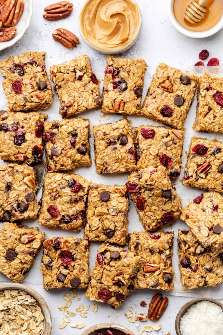 Overhead view of a batch of trail mix bars cut into squares showing pieces of chocolate, nuts, and dried cranberries.