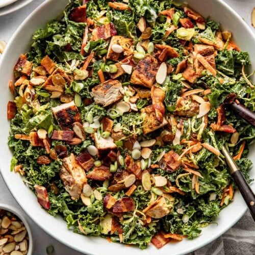 Overhead view chopped salad with kale, chicken, veggies, and bbq ranch dressing serving in white bowl