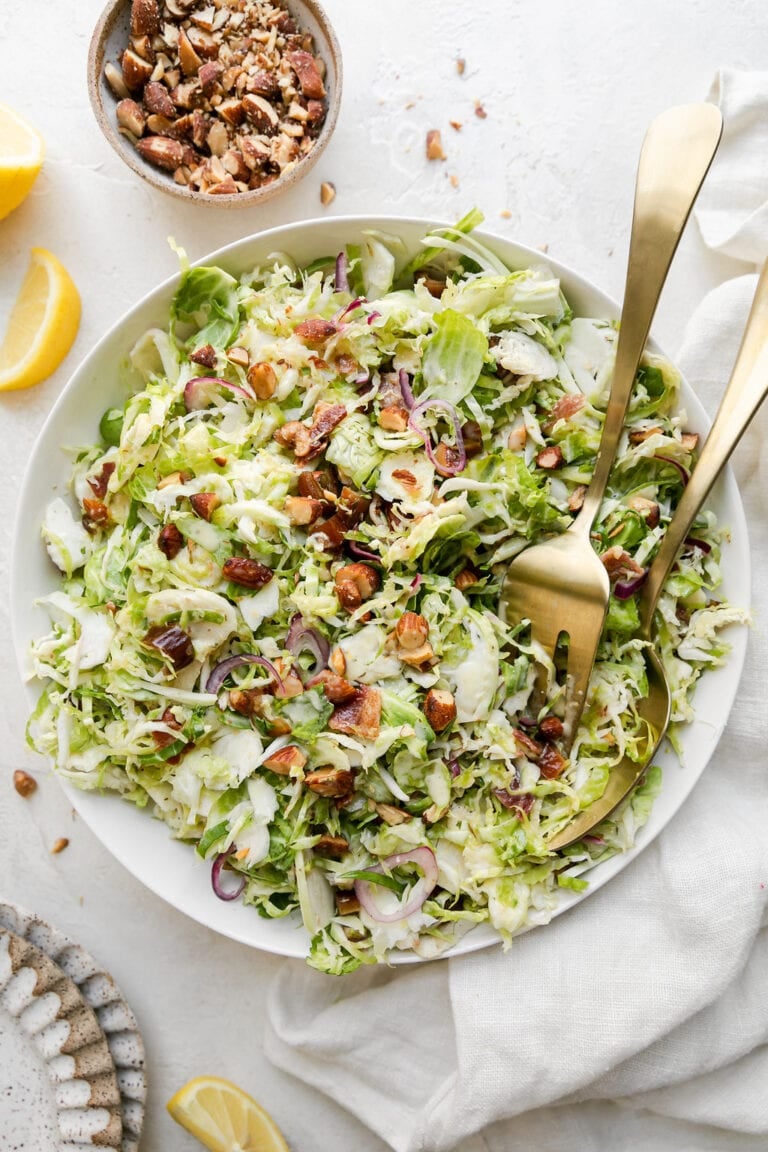 Overhead view of a brussels sprouts slaw topped with almonds and date pieces. 