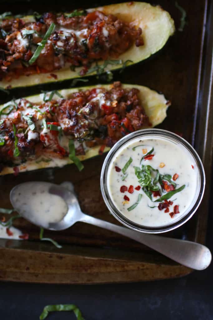 Overhead view of stuffed zucchinis with Creamy Italian Dressing in a small glass jar