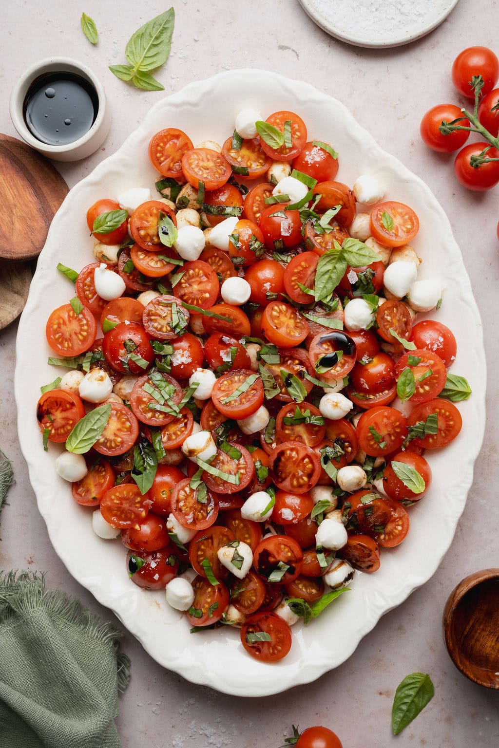 A caprese salad topped with a drizzle of balsamic vinegar on a white platter.