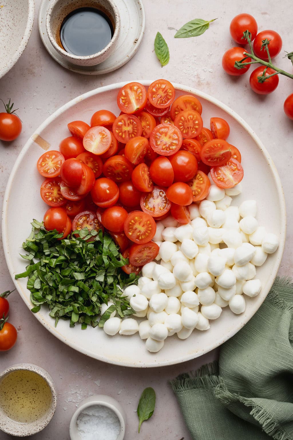 A plate of halved cherry tomatoes, fresh basil, and mozzarella balls.