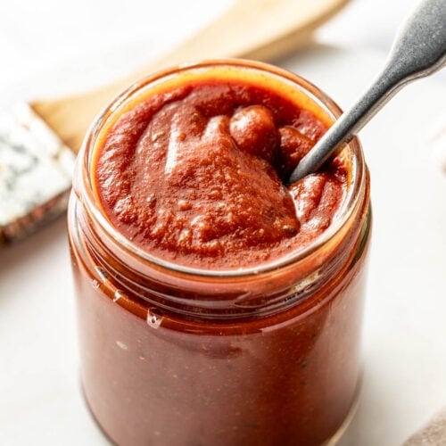 Overhead view of a glass jar filled with Homemade BBQ Sauce and a spoon in the jar.