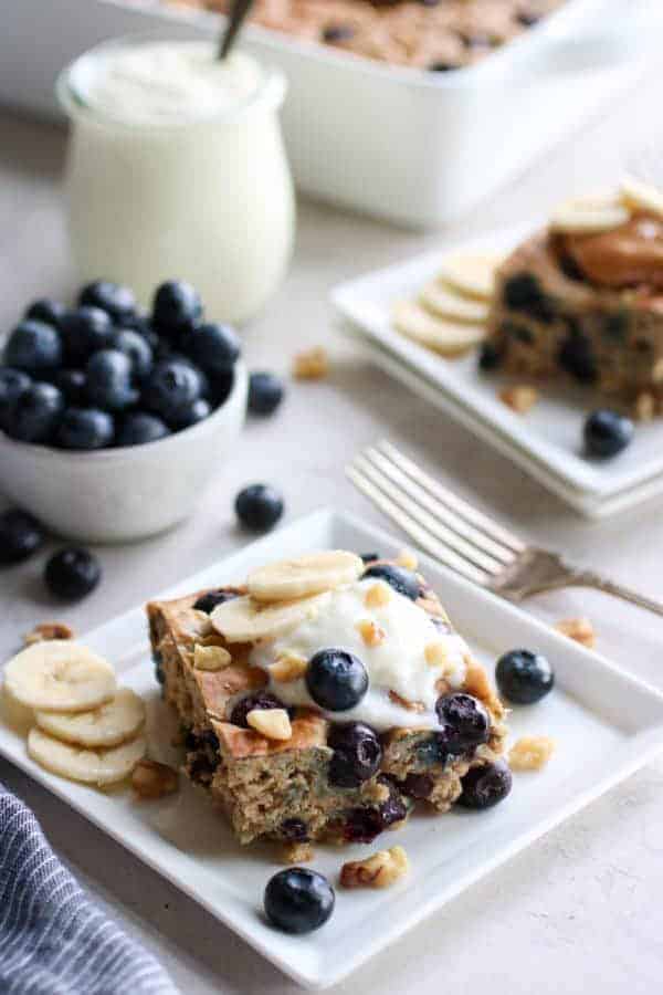 Blueberry banana walnut muffin bars on a plate topped with greek yogurt. 