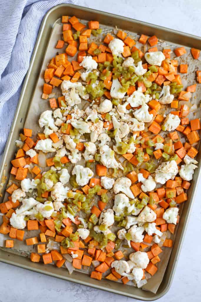 Sheet pan filled with diced sweet potatoes, cauliflower, and green chilies