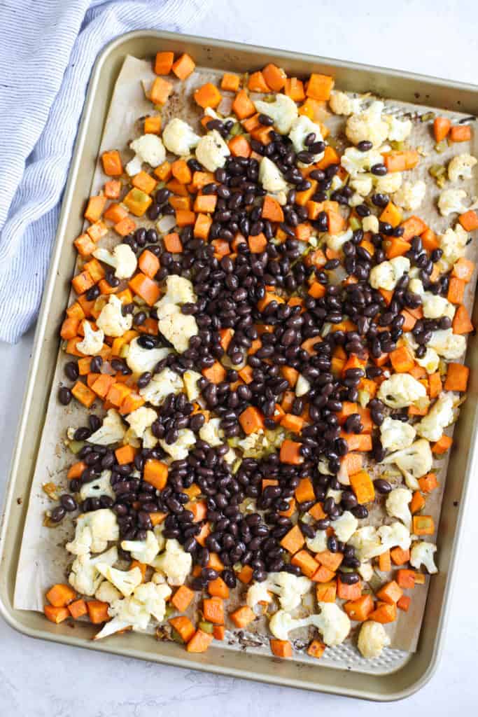 Sheet pan filled with diced sweet potatoes, cauliflower, and black beans