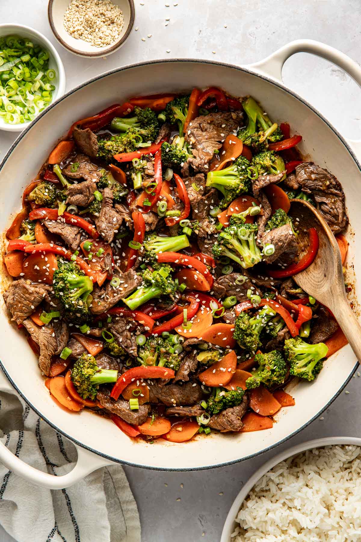 Overhead view of a skillet filled with Steak Stir Fry sprinkled with sesame seeds and green onions. 