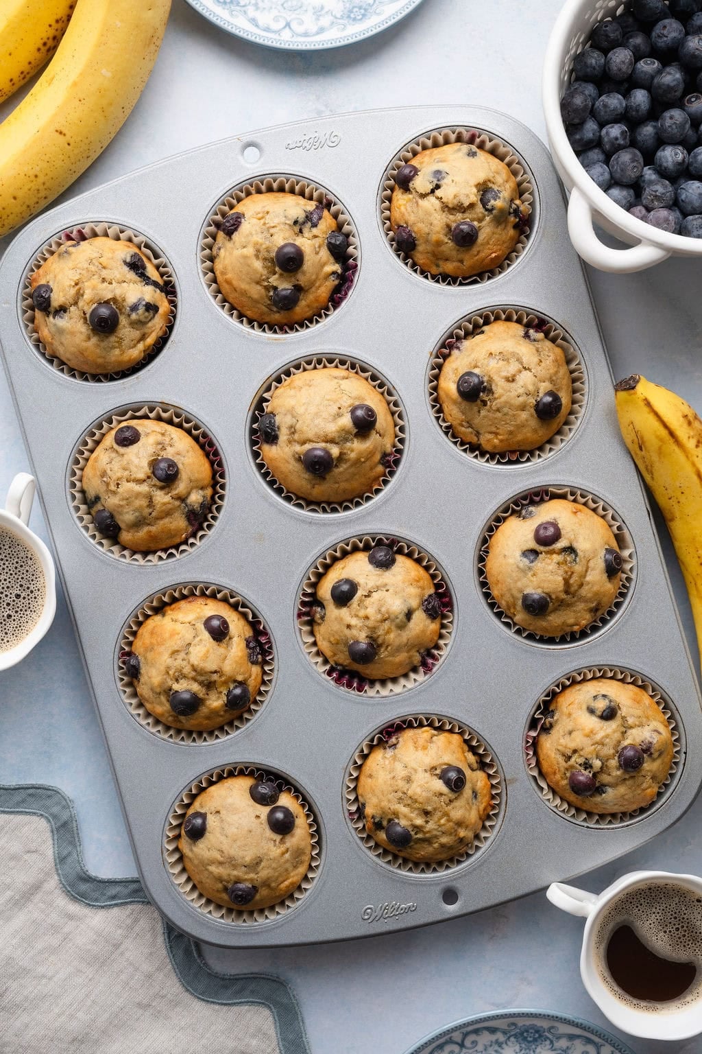 Overhead view of a muffin pan filled with freshly baked Banana Blueberry Muffins. 
