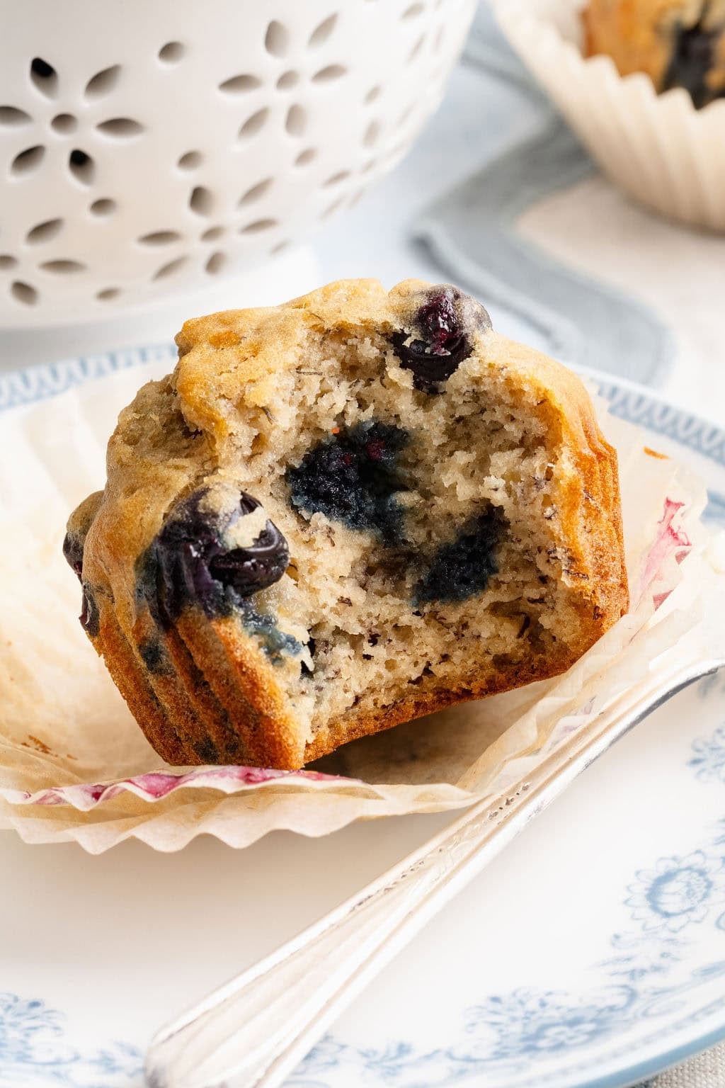 Close up view of a banana blueberry muffin with a bite out of it to show the moist texture inside. 