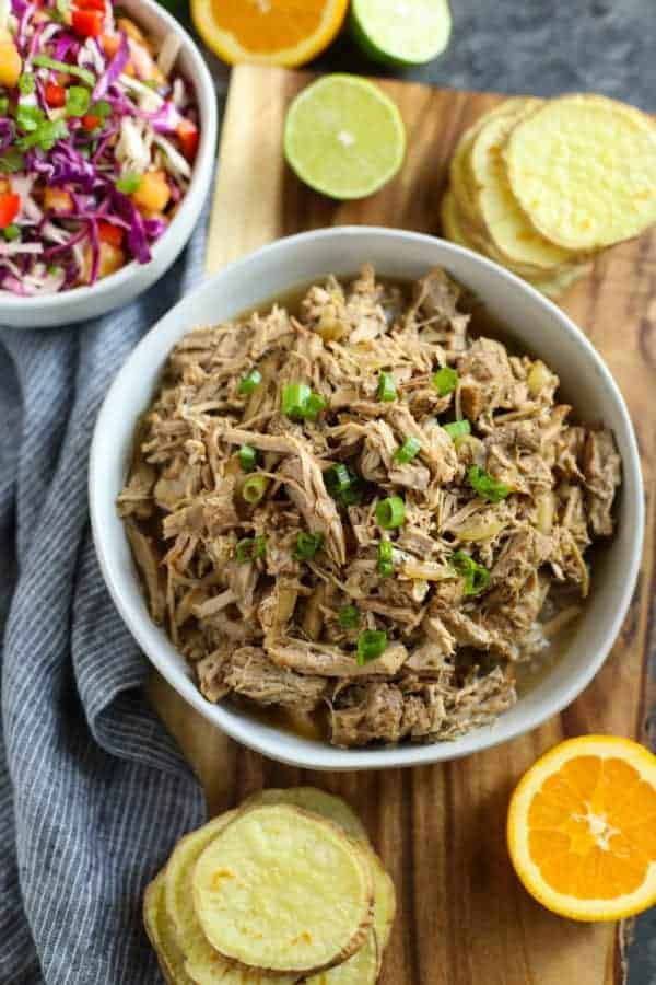 A large white bowl of Slow Cooker Citrus Herb Pork topped with green onions