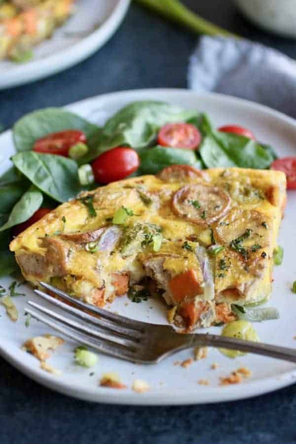 Sweet Potato Chicken Sausage Egg Bake on a plate with spinach and tomatoes on a plate 