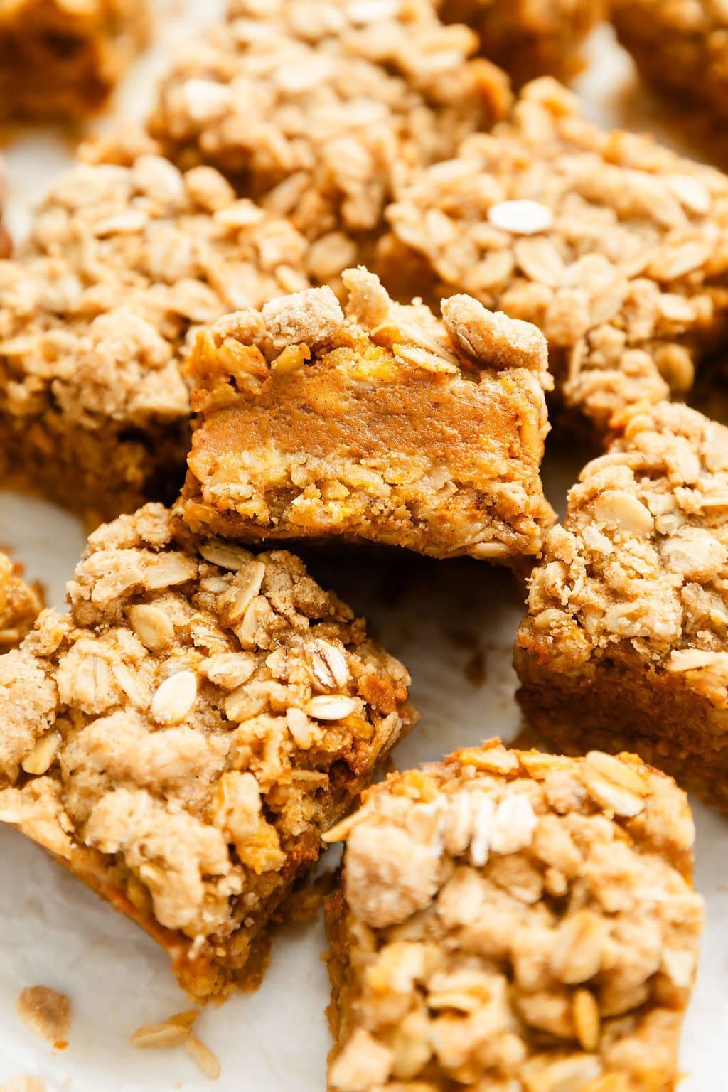 Close up view of a batch of pumpkin pie bars showing the middle layer of pumpkin filling and oat texture on the outside.