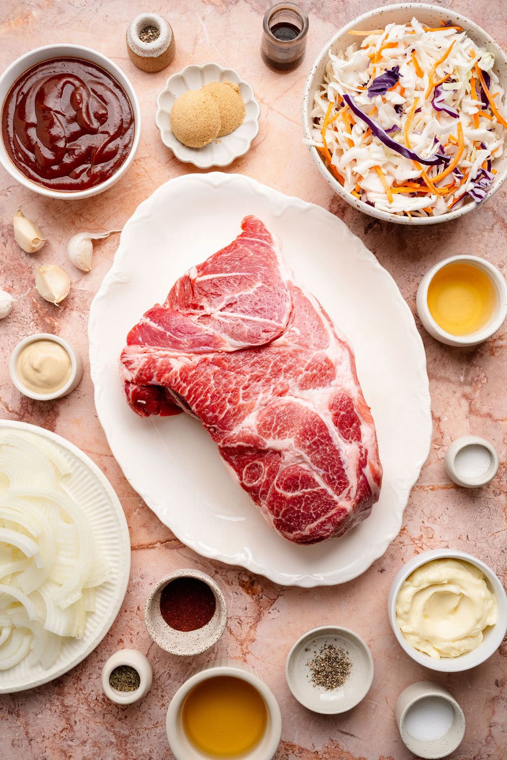 Overhead view of a variety of ingredients for Pulled Pork Sliders on a countertop in different sized bowls.