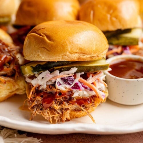 Close up view of pork sliders topped with creamy coleslaw.