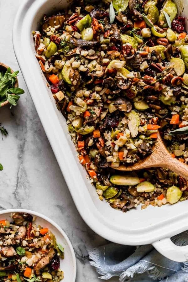 Cauliflower stuffing with brussels sprouts, mushrooms, and pecans in a white baking dish