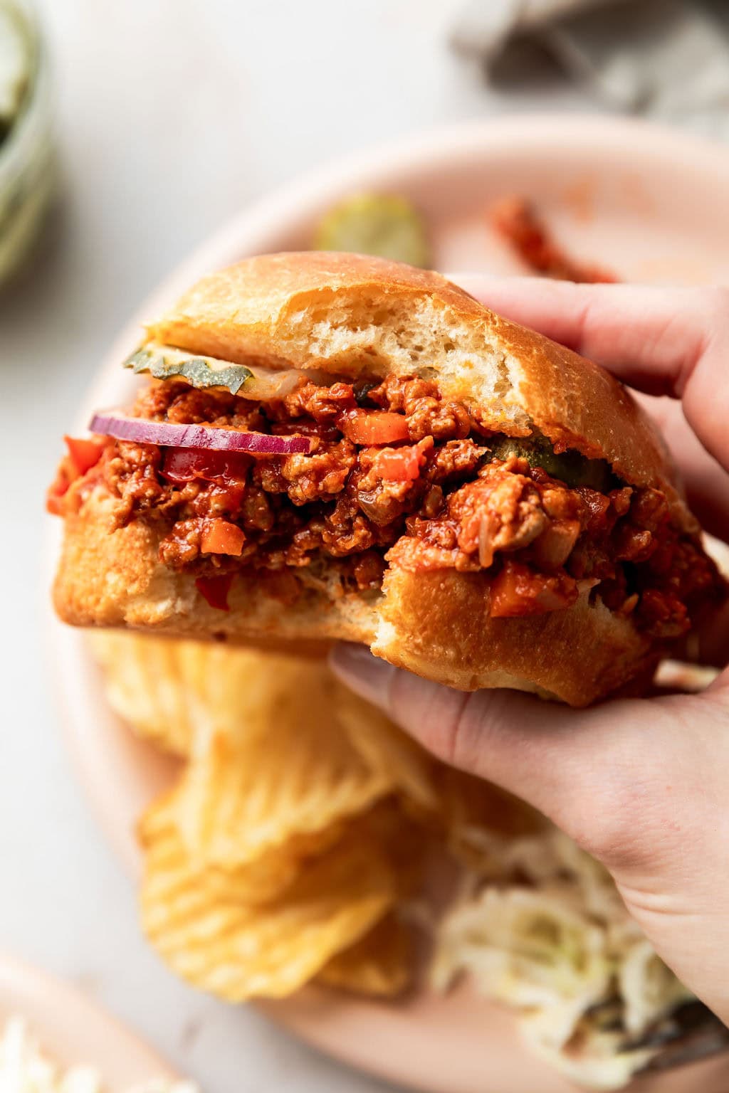 Close up view of a ground turkey sloppy joe on a bun with a large bite taken out of it. 