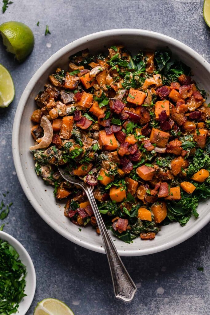 An overhead view of Warm Chipotle Lime Sweet Potato Salad in a light gray serving bowl garnished with cilantro.