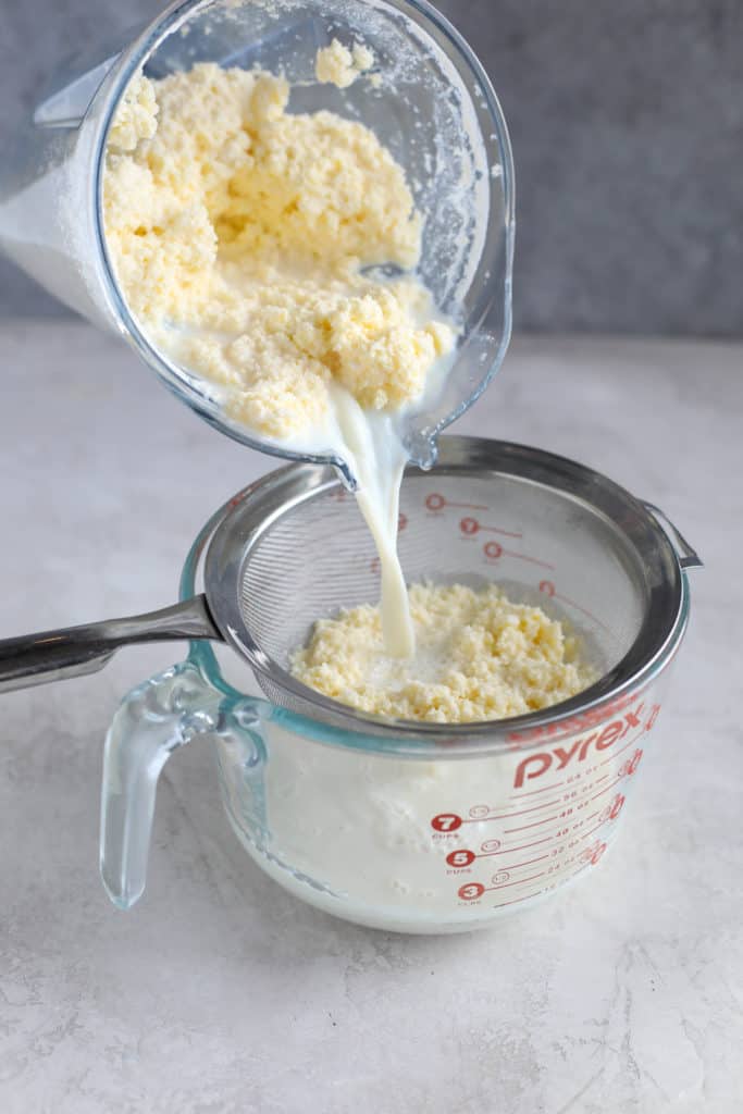 Pouring butter and buttermilk out of a blender into a strainer