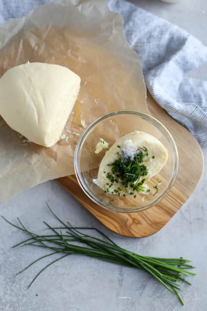 A ball of butter cut in 2 pieces with fresh chives on the side