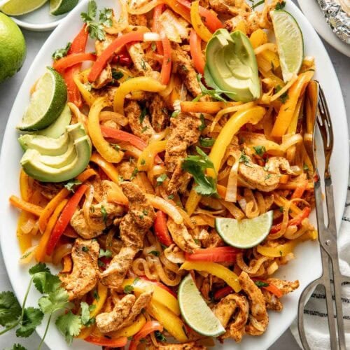 Overhead view of a platter filled with Chicken Fajitas, peppers, and onions.