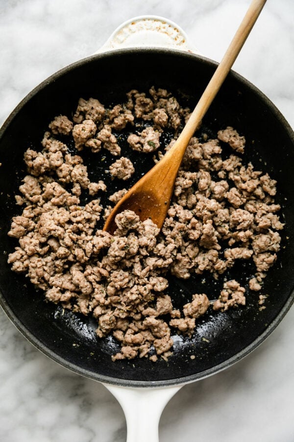 Overhead view of a pan filled with ground sausage that is browning