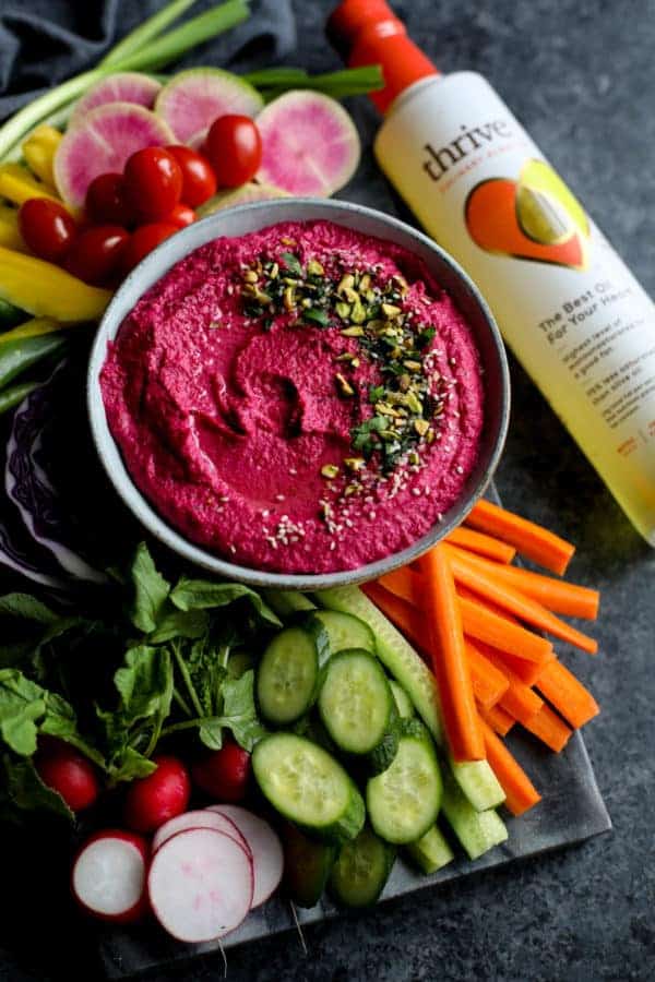Overhead view of a bowl of Beet Hummus surrounded by raw vegetables