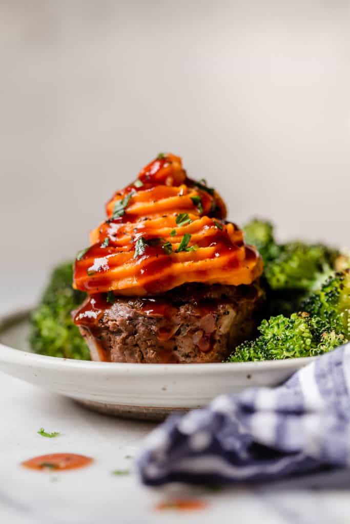 Meatloaf muffin with sweet potato piped on top surrounded with broccoli on a plate. 1 of 10 Quick and Easy Dinner Ideas.